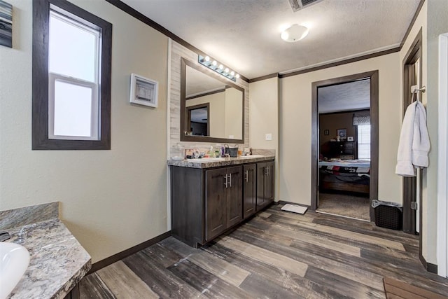 full bath featuring crown molding, ensuite bathroom, vanity, a textured ceiling, and wood finished floors