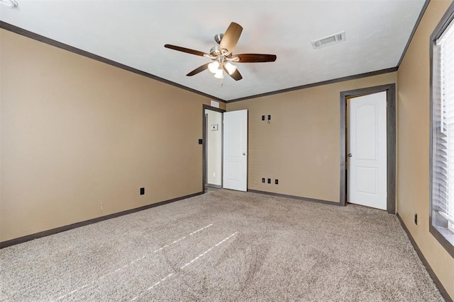 spare room with ceiling fan, light carpet, visible vents, baseboards, and crown molding