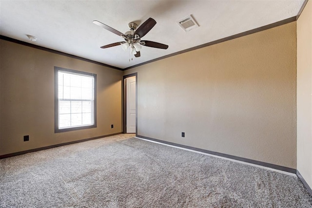 carpeted empty room with ornamental molding, visible vents, baseboards, and a ceiling fan