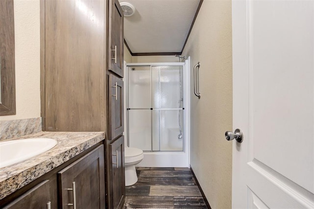 full bath featuring a shower with door, vanity, toilet, and wood finished floors