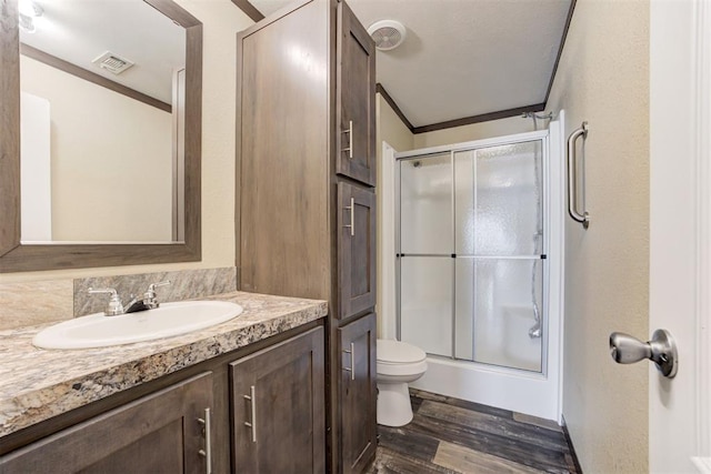 bathroom with visible vents, toilet, a stall shower, vanity, and wood finished floors