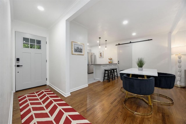 foyer entrance featuring dark wood-type flooring, a barn door, and ornamental molding