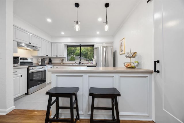 kitchen with white cabinets, stainless steel appliances, and a breakfast bar area