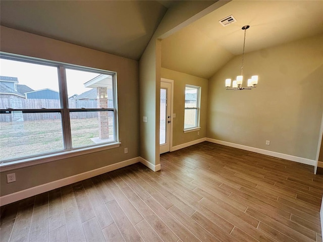 empty room with wood finished floors, visible vents, baseboards, an inviting chandelier, and lofted ceiling