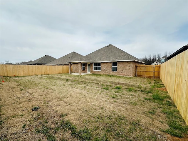 back of property featuring a patio, a lawn, a fenced backyard, and brick siding