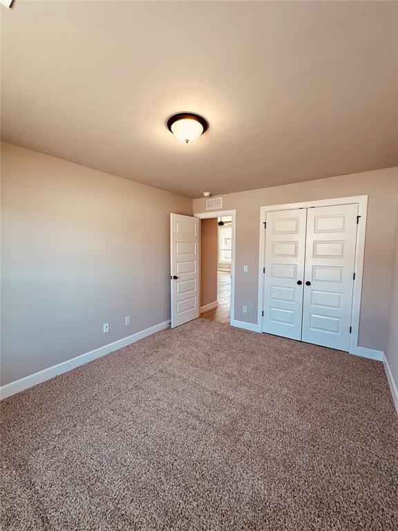 unfurnished bedroom featuring baseboards, visible vents, a closet, and carpet floors