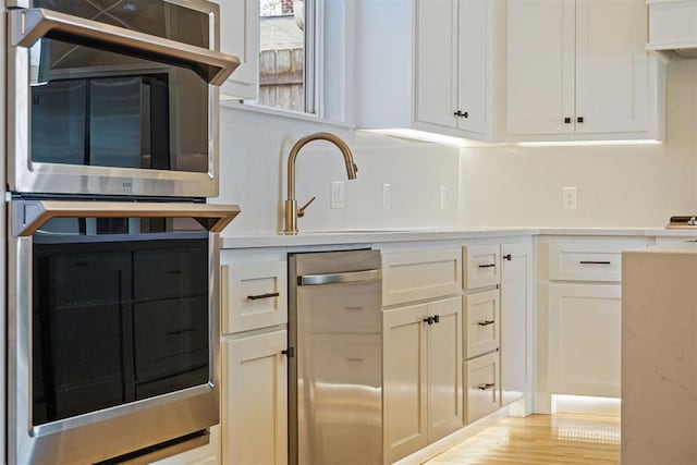 kitchen featuring white cabinetry, double oven, and light hardwood / wood-style floors