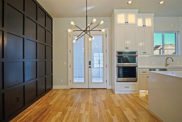 doorway to outside with french doors, sink, a notable chandelier, and light hardwood / wood-style flooring