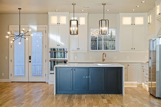 kitchen with white cabinetry, sink, decorative light fixtures, and stainless steel appliances