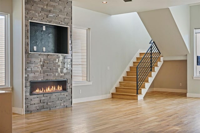 unfurnished living room featuring plenty of natural light, a large fireplace, and light wood-type flooring