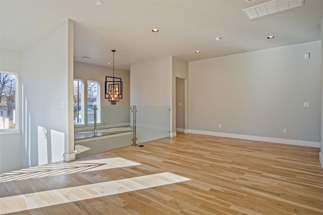 empty room featuring an inviting chandelier and light hardwood / wood-style flooring