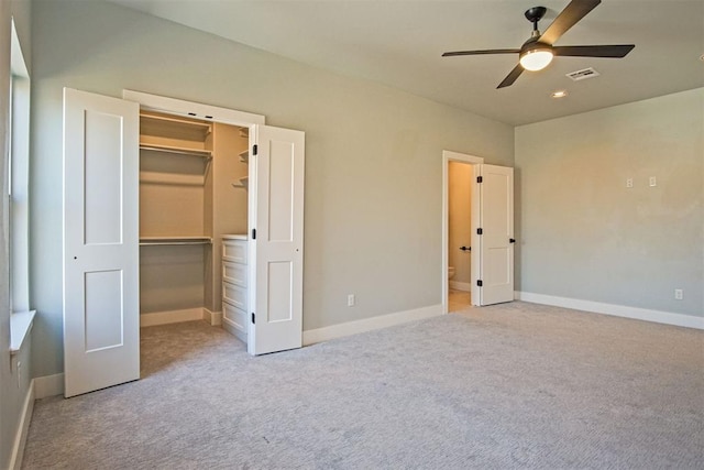 unfurnished bedroom with ensuite bath, ceiling fan, a walk in closet, light colored carpet, and a closet