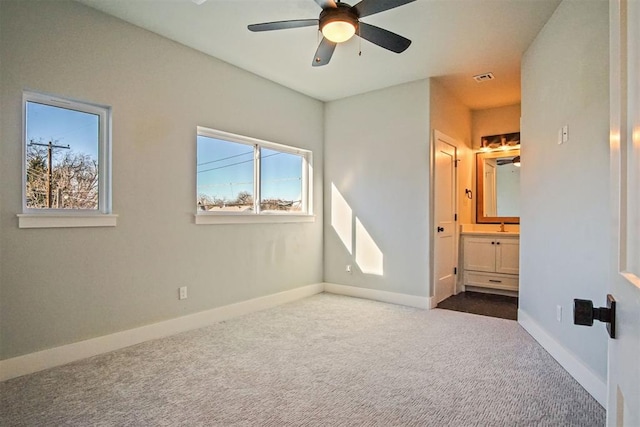 unfurnished bedroom featuring ceiling fan, carpet floors, sink, and ensuite bath