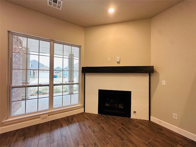 unfurnished living room with a brick fireplace and dark hardwood / wood-style floors