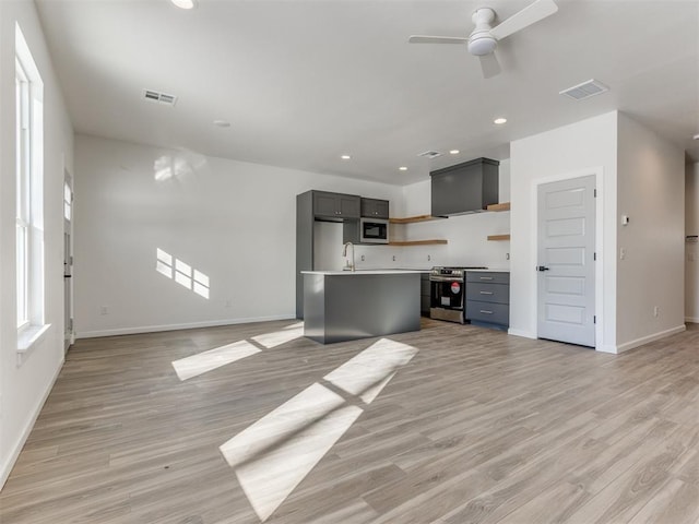 kitchen featuring light hardwood / wood-style flooring, stainless steel range oven, ceiling fan, gray cabinets, and a kitchen island