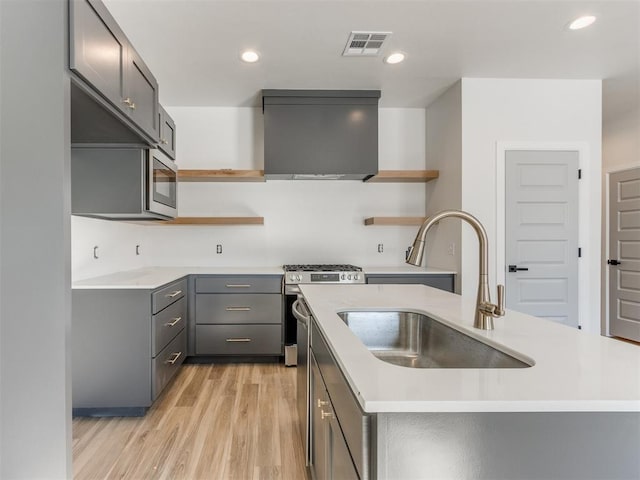 kitchen with open shelves, wall chimney range hood, a sink, and visible vents