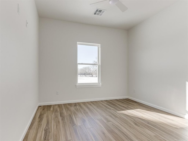 spare room with light wood-type flooring, ceiling fan, visible vents, and baseboards