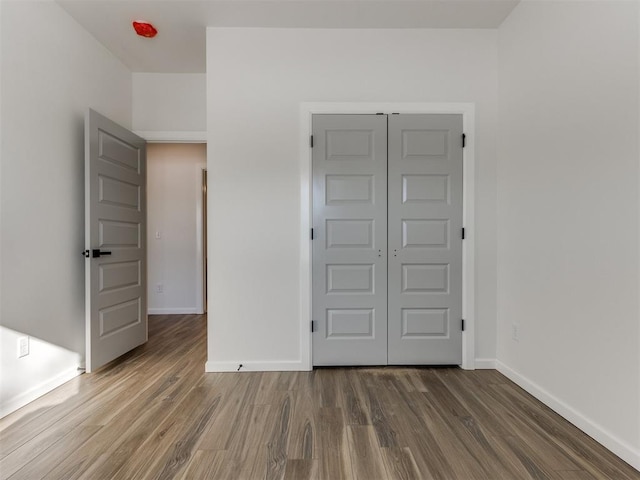 unfurnished bedroom with a closet, baseboards, and wood finished floors