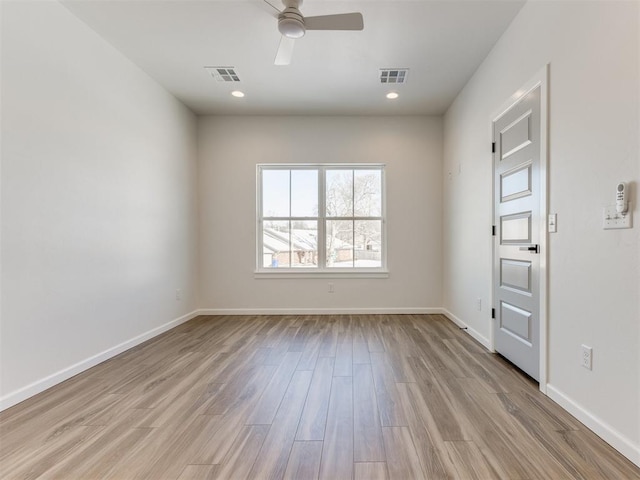 spare room with baseboards, visible vents, and wood finished floors