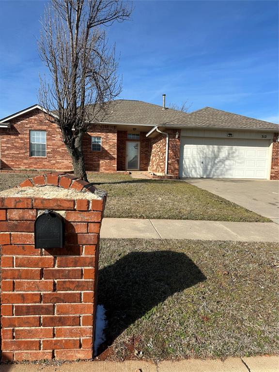 view of front of house with brick siding, concrete driveway, a shingled roof, a front yard, and an attached garage