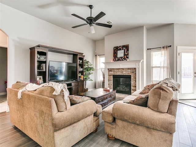 living room with ceiling fan, a wealth of natural light, wood-type flooring, and a fireplace