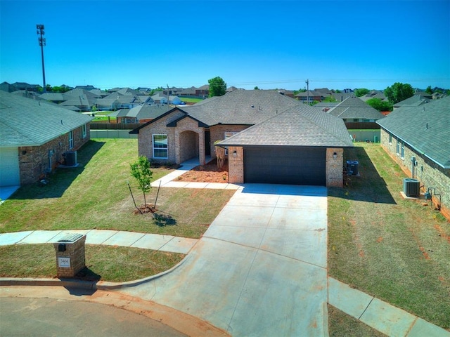 view of front of home featuring a garage, cooling unit, and a front yard