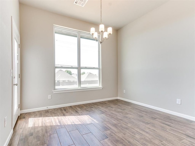 spare room with light hardwood / wood-style flooring and a chandelier