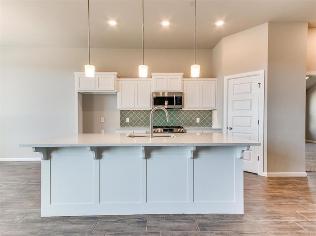 kitchen with a large island, white cabinets, hanging light fixtures, and decorative backsplash