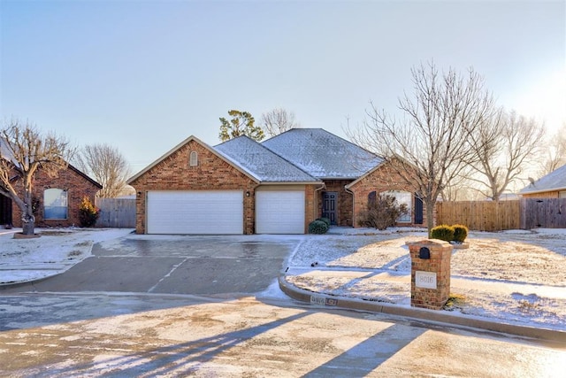 ranch-style house featuring an attached garage, fence, and concrete driveway