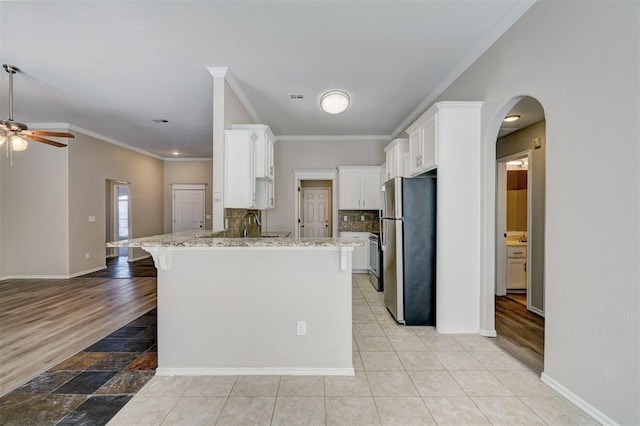 8016 Heather Glen Dr, Yukon, OK 73099 - kitchen featuring white cabinets, a ceiling fan, arched walkways, freestanding refrigerator, and a peninsula