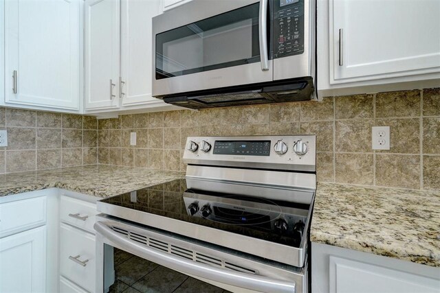 8016 Heather Glen Dr, Yukon, OK 73099 - kitchen featuring white cabinets, decorative backsplash, light stone counters, and appliances with stainless steel finishes