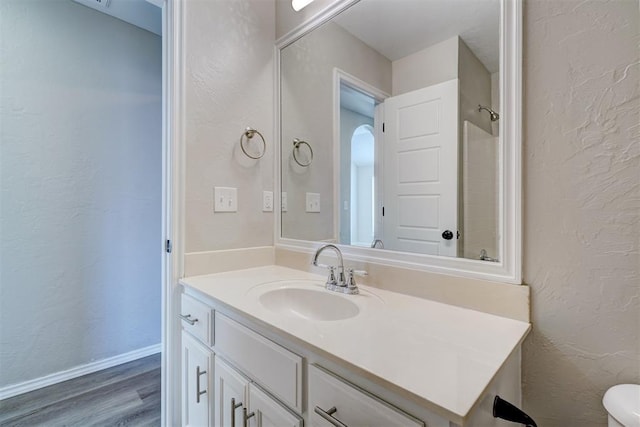 8016 Heather Glen Dr, Yukon, OK 73099 - bathroom with wood finished floors, a textured wall, toilet, vanity, and baseboards