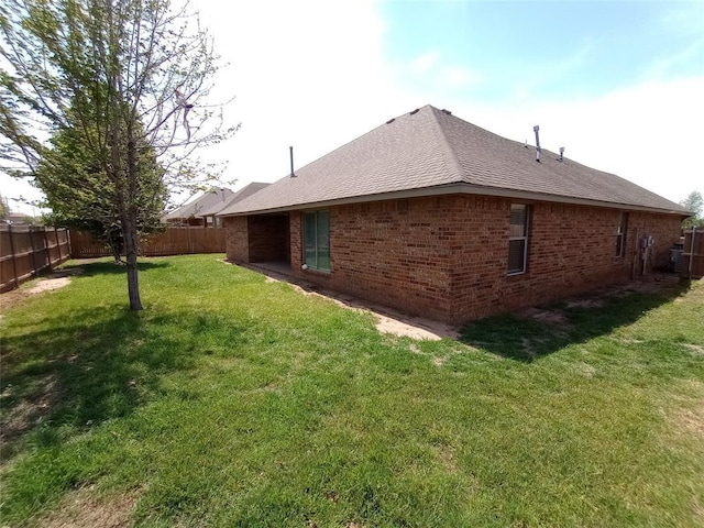 8016 Heather Glen Dr, Yukon, OK 73099 - view of home's exterior with brick siding, a yard, a shingled roof, and a fenced backyard