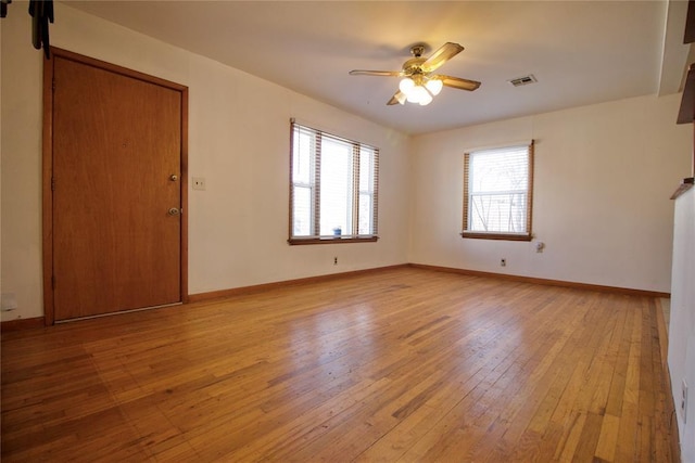 spare room featuring a ceiling fan, visible vents, light wood-style flooring, and baseboards