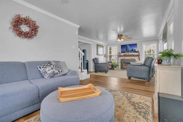 living room featuring a brick fireplace, hardwood / wood-style floors, crown molding, and ceiling fan