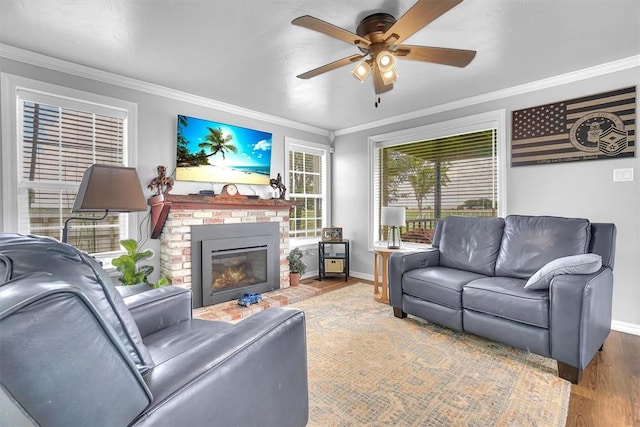 living room featuring hardwood / wood-style floors, ceiling fan, ornamental molding, and a fireplace