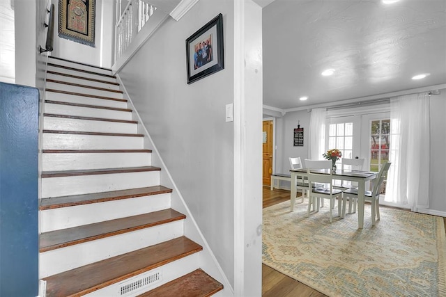 stairs featuring french doors, hardwood / wood-style floors, and crown molding