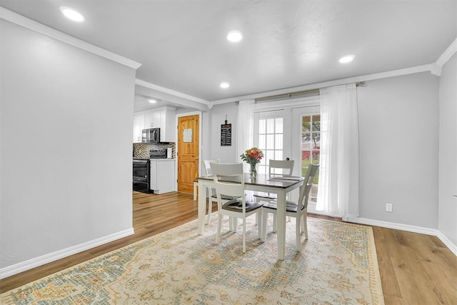 dining room featuring light wood-type flooring, french doors, and crown molding