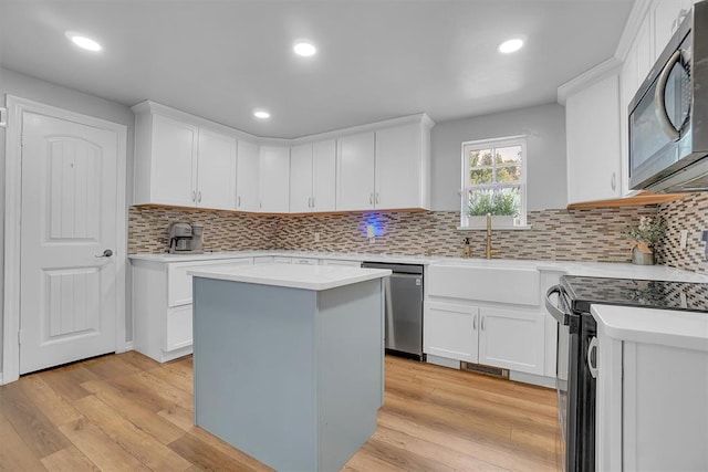 kitchen with a kitchen island, stainless steel appliances, white cabinets, and light hardwood / wood-style flooring