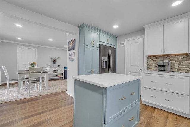 kitchen with backsplash, stainless steel refrigerator with ice dispenser, light wood-type flooring, a kitchen island, and white cabinets