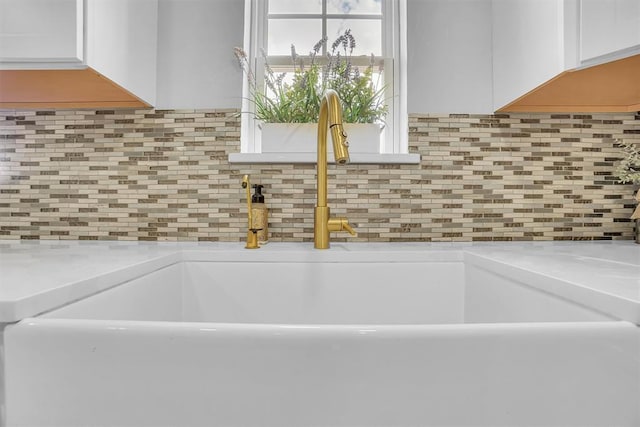 room details featuring white cabinets, light stone countertops, and sink