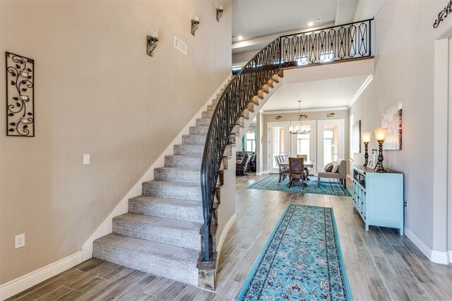 3910 Sienna Rdg, Newcastle, OK 73065 - staircase featuring a notable chandelier, a high ceiling, wood finish floors, baseboards, and visible vents