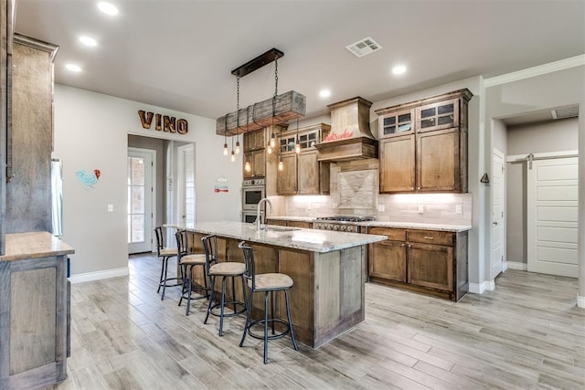 3910 Sienna Rdg, Newcastle, OK 73065 - kitchen featuring visible vents, custom exhaust hood, stainless steel appliances, tasteful backsplash, and a barn door
