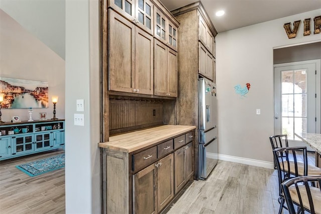 3910 Sienna Rdg, Newcastle, OK 73065 - kitchen with baseboards, light wood-style flooring, glass insert cabinets, and stainless steel fridge