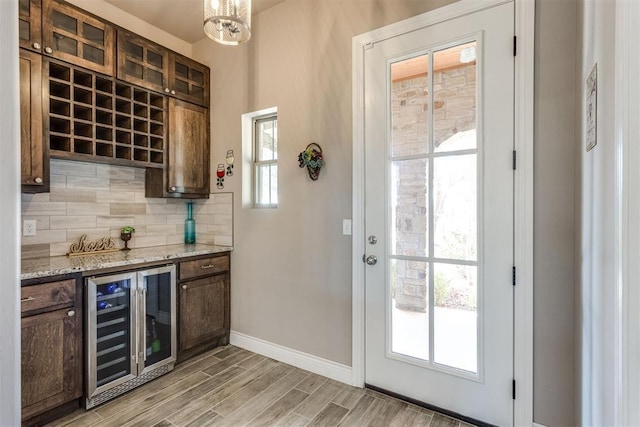 3910 Sienna Rdg, Newcastle, OK 73065 - bar with wine cooler, a bar, baseboards, light wood-style floors, and decorative backsplash