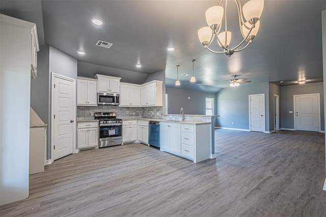 kitchen featuring appliances with stainless steel finishes, open floor plan, decorative light fixtures, a peninsula, and white cabinetry