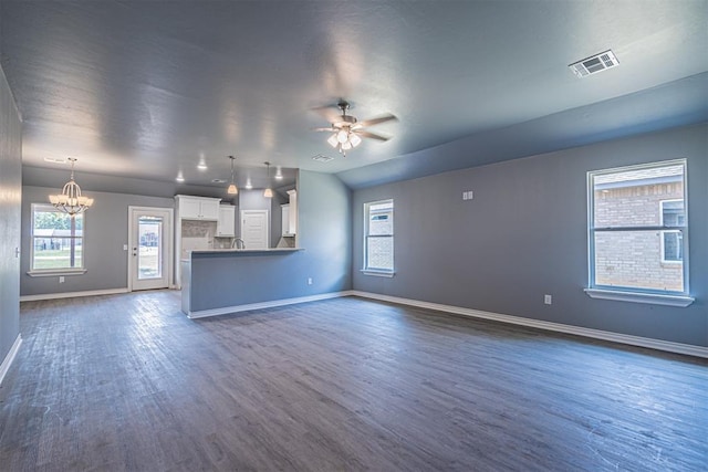 unfurnished living room featuring dark wood finished floors, visible vents, a sink, baseboards, and ceiling fan with notable chandelier