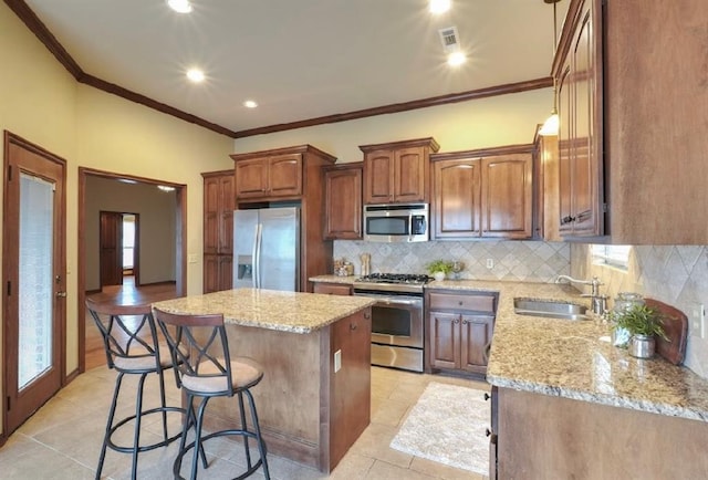 kitchen featuring stainless steel appliances, decorative backsplash, a center island, light tile patterned floors, and sink