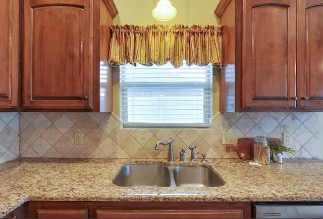 kitchen featuring stainless steel dishwasher, sink, light stone counters, and backsplash