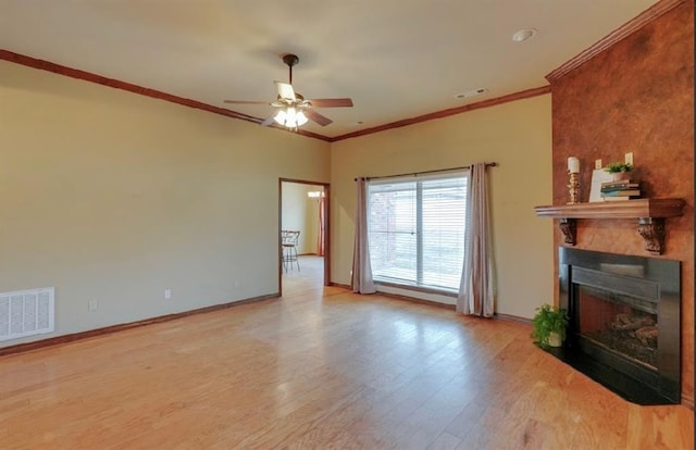 unfurnished living room featuring a large fireplace, ornamental molding, and light wood-type flooring